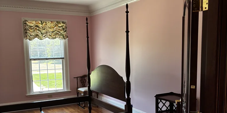 Bedroom with fresh pink walls and white crown molding after interior painting in Hudson, Ohio