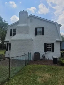 White painted brick exterior with black shutters and chimney by Chagrin Falls Painting Company