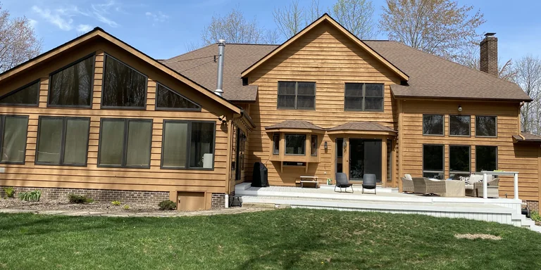 Cedar-sided home with freshly stained siding and a rear patio