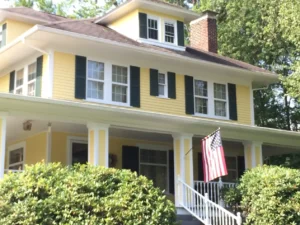 Professional exterior painting of a yellow residential home with white trim and black shutters in Cleveland.