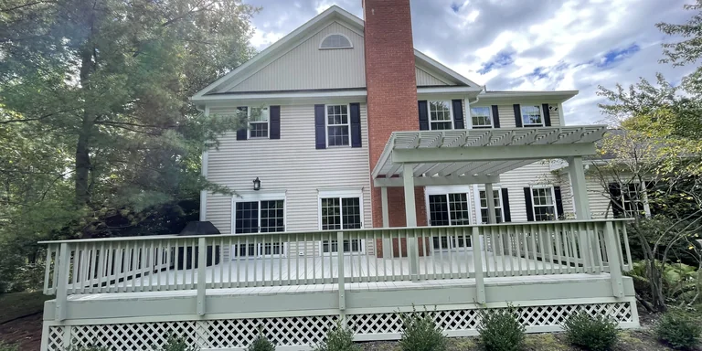 Cream colonial with black shutters, a pergola and a freshly painted deck railing in Hudson, Ohio