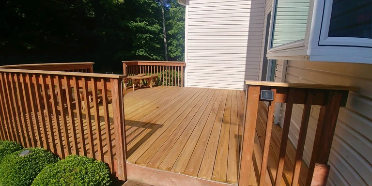 Cedar-toned deck and railing after staining beside a cream-sided home in Kirtland, Ohio