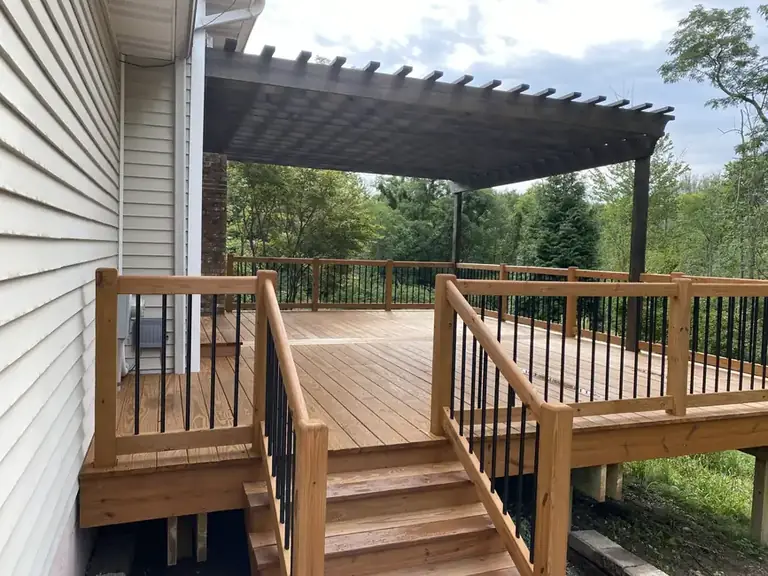 Freshly stained wood deck with a pergola and black metal balusters, deck staining in Northeast Ohio