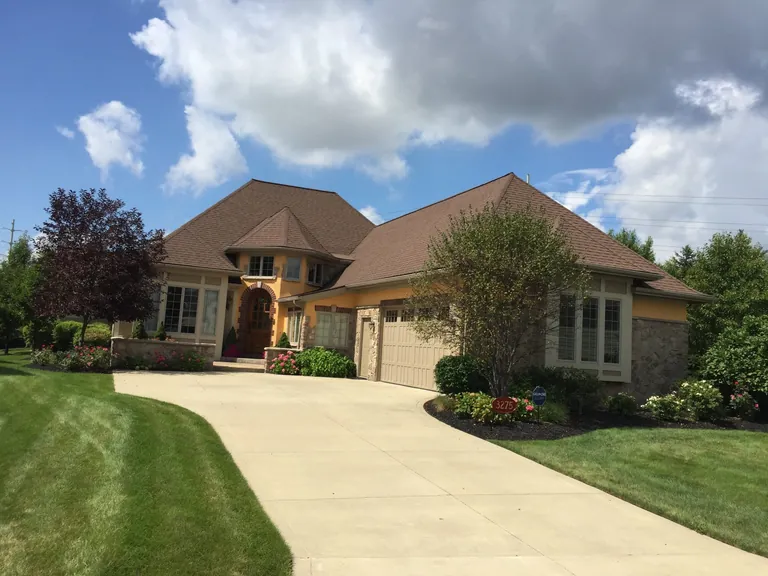 Clean concrete driveway and stone-front home after pressure washing in Hudson, Ohio
