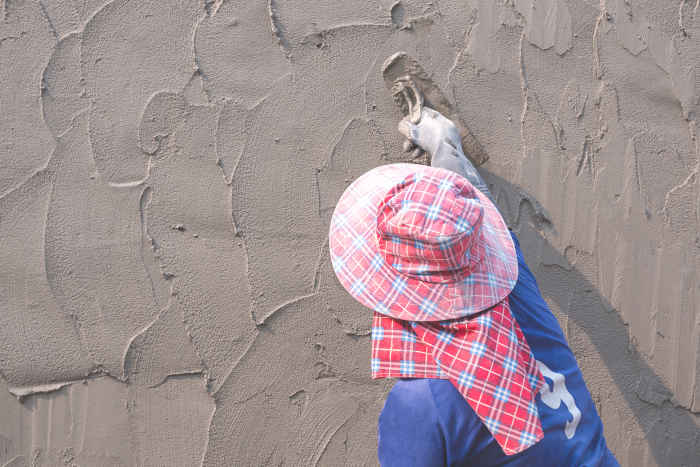 Worker applying a flexible coating on a stucco wall