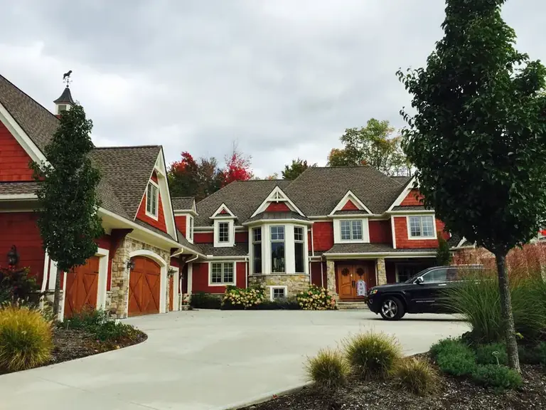 Red two-story home with stone accents and freshly painted trim, exterior house painting in Chagrin Falls, Ohio