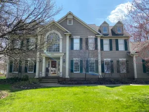 Tan vinyl siding colonial home with green shutters and white trim painted by Chagrin Falls Painting Company