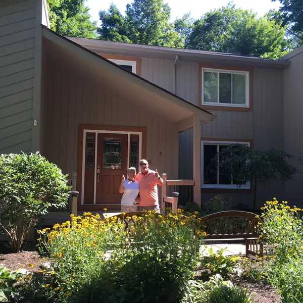Happy homeowners giving thumbs up in front of freshly painted home exterior by Chagrin Falls Painting Company