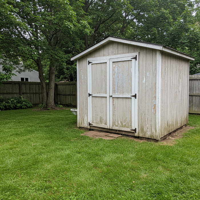 Backyard shed with peeling and fading paint showing signs of failure