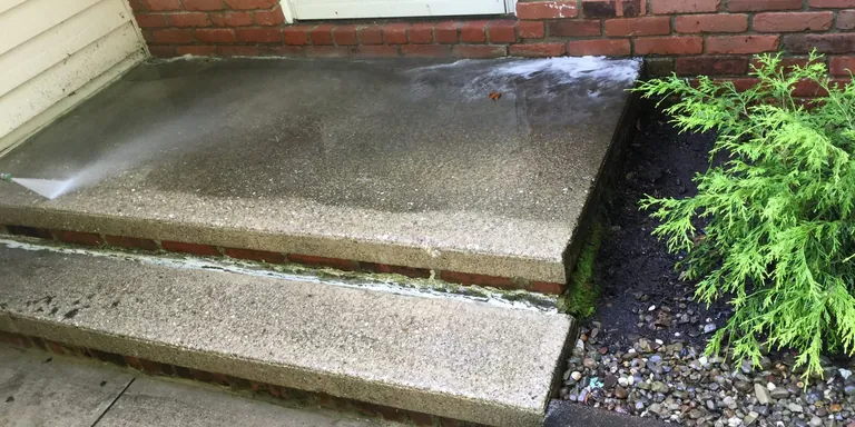 Concrete front steps mid-wash beside a brick home, pressure washing in Chardon, Ohio