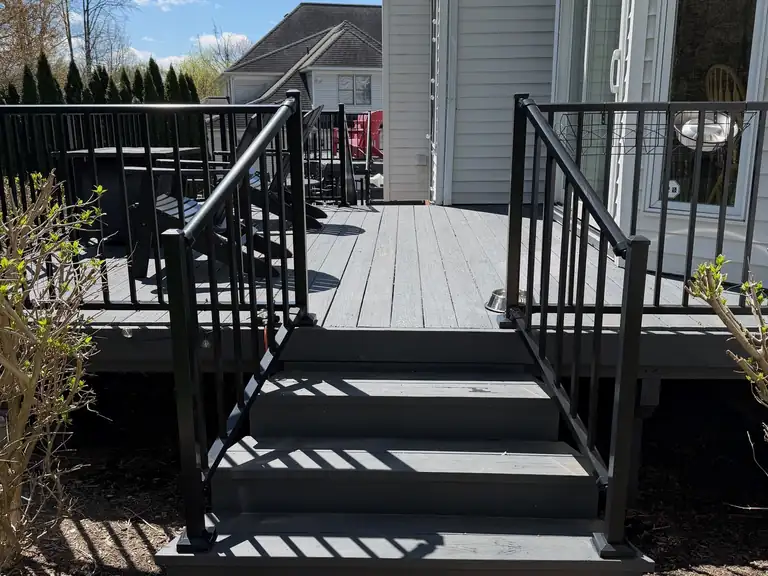 Deck steps finished in solid gray stain with black metal railings, Northeast Ohio