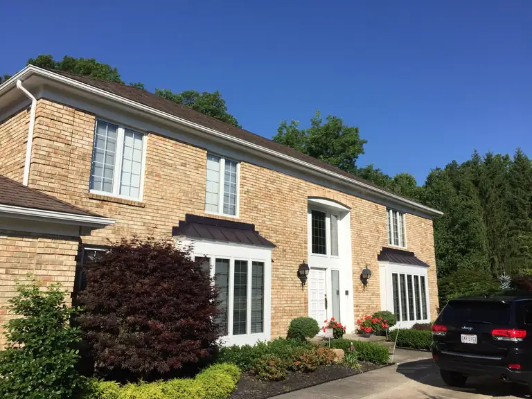 Tan brick two-story home with freshly painted white trim, windows and front door, Northeast Ohio