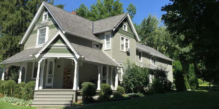 Sage green Victorian farmhouse with white trim after exterior painting in Hiram, Ohio