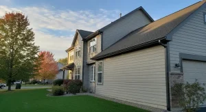 Dark painted gutters and downspouts on gray lap siding home
