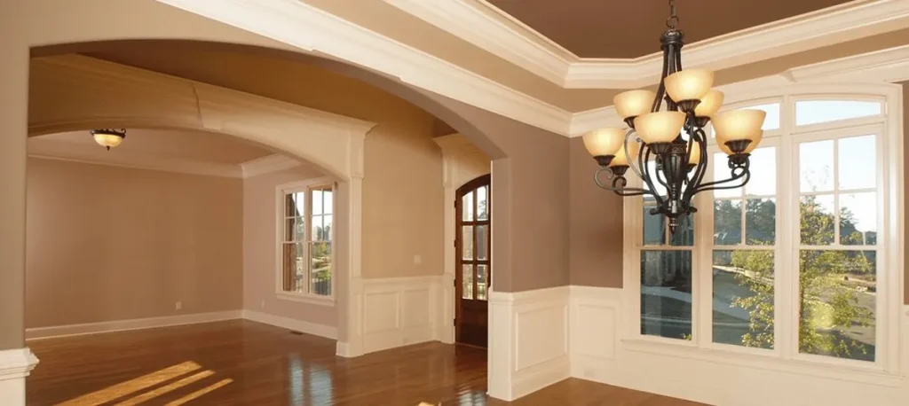 Formal living room with warm tan walls, white wainscoting, tray ceiling, and hardwood floors representing house painting services in Highland Heights, Ohio by Chagrin Falls Painting Company