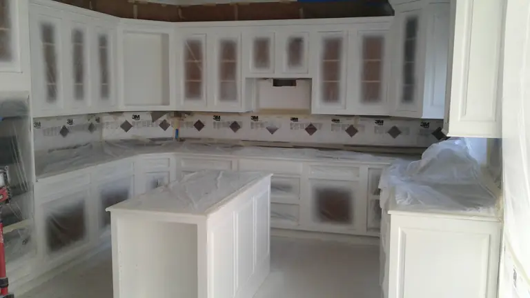 Kitchen masked off while the cabinets are spray painted, cabinet refinishing by Chagrin Falls Painting