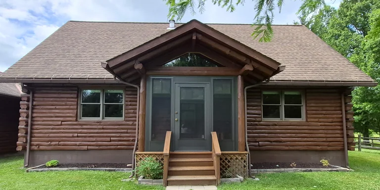 Freshly stained log home with a screened entry porch in Hiram, Ohio