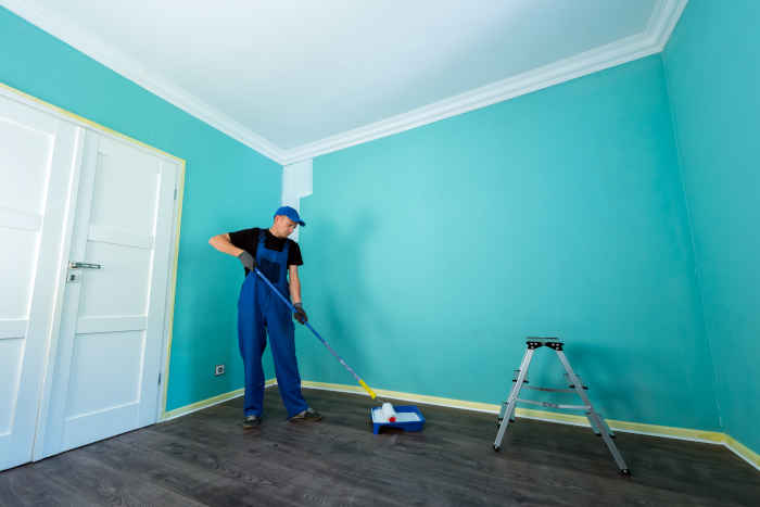 A man using a paint roller to paint a room, representing Sherwin-Williams' high-quality interior paints.