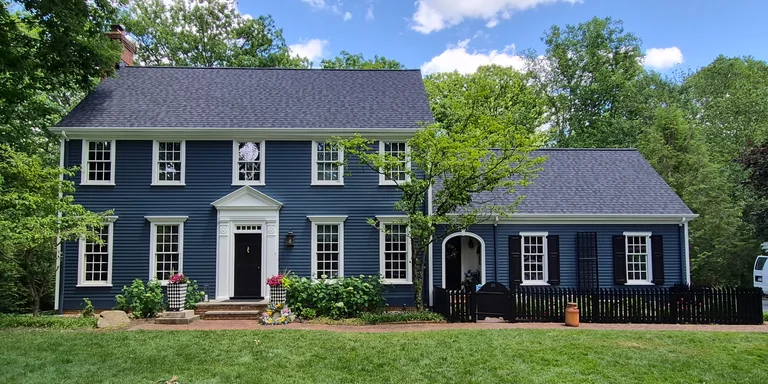Navy colonial home with white trim and a black picket fence after exterior painting in Aurora, Ohio