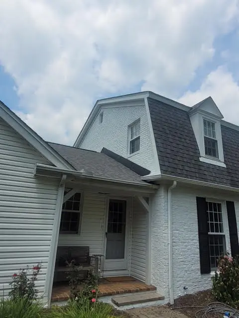 White painted brick home with covered entry and black shutters by Chagrin Falls Painting Company