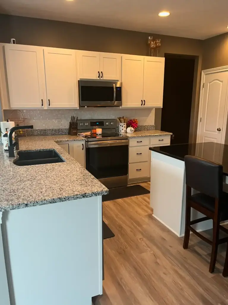 Kitchen with white painted cabinets and a black island, kitchen and cabinet repaint in Parma, Ohio