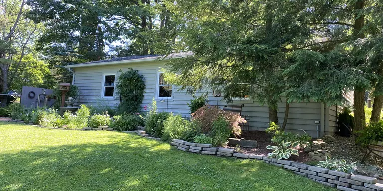 Gray ranch home with white window trim and a perennial garden bed in Willoughby Hills, Ohio