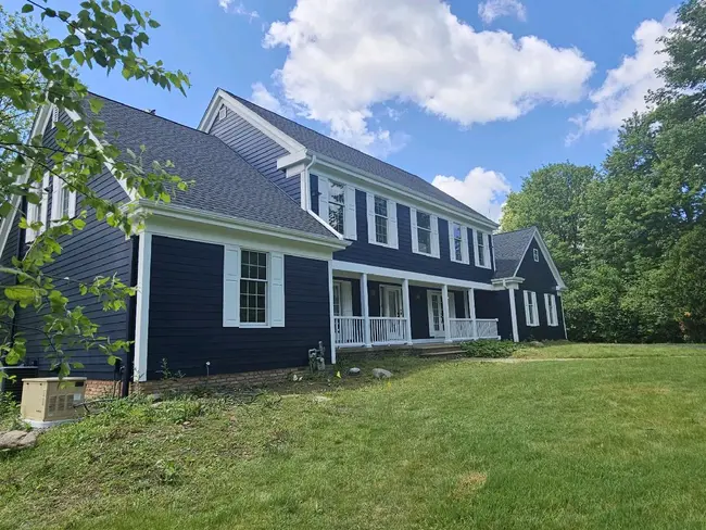 White shutters on navy blue lap siding home painted by Chagrin Falls Painting Company, Ohio