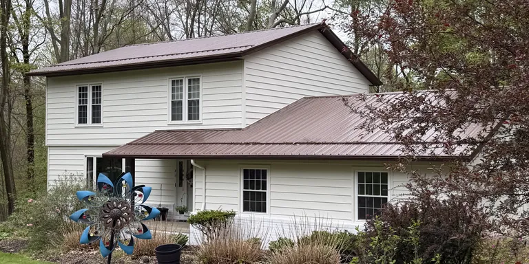 White two-story home with a brown metal roof after an exterior repaint