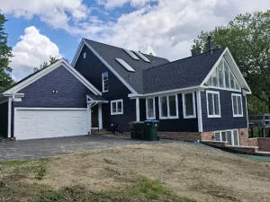 White window trim on navy blue lap siding home with white garage door by Chagrin Falls Painting Company