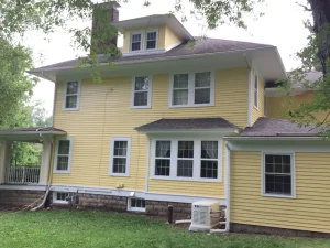 Yellow wood lap siding rear exterior with white window trim painted by Chagrin Falls Painting Company