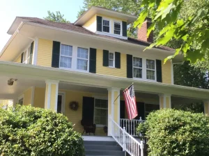 Yellow wood lap siding home with green shutters and white trim painted by Chagrin Falls Painting Company