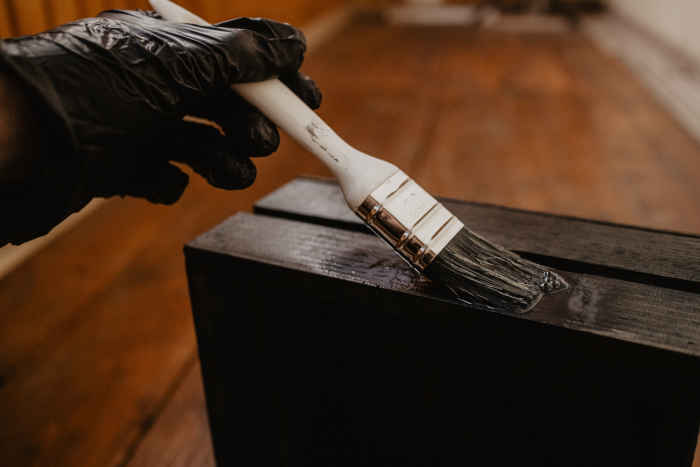 A person applying wood stain, highlighting Sherwin-Williams' expertise in performance coatings and wood finishes.