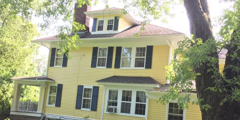Yellow foursquare home with black shutters after exterior painting in Bainbridge, Ohio
